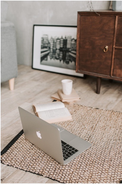 Apple laptop on the floor next to a book and coffee