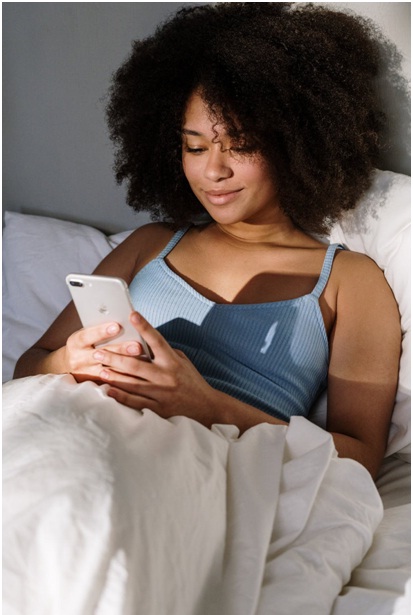 Woman in bed holding an iPhone