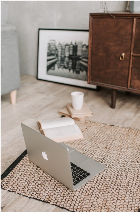 Laptop on the floor with a book and coffee next to it