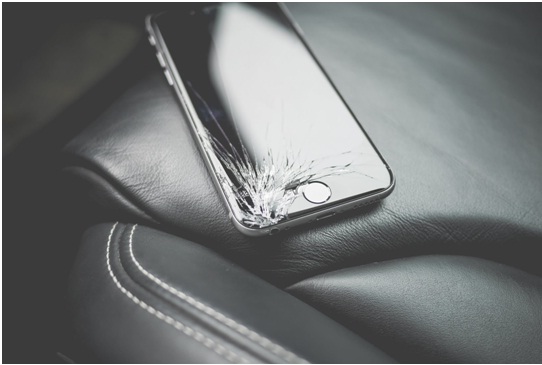 iPhone with smashed screen on black car seat