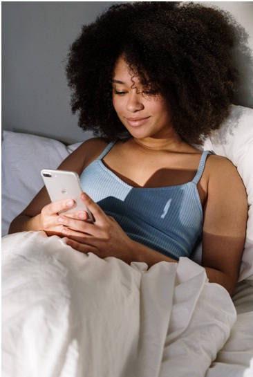 Woman in bed holding an iPhone
