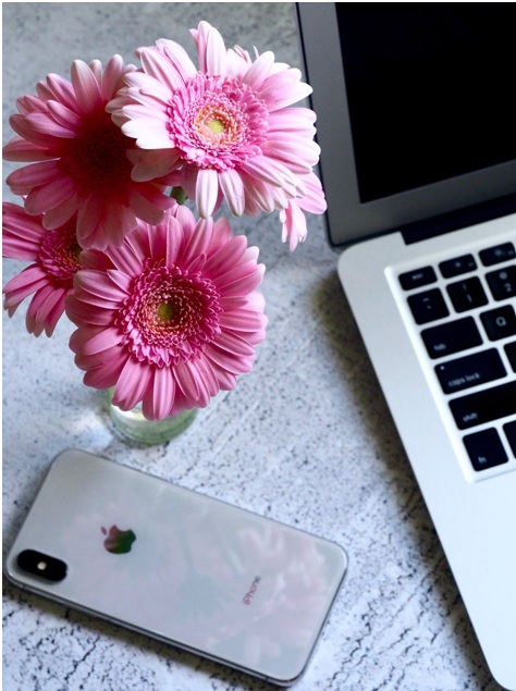 Pink flowers in a vase next to iPhone